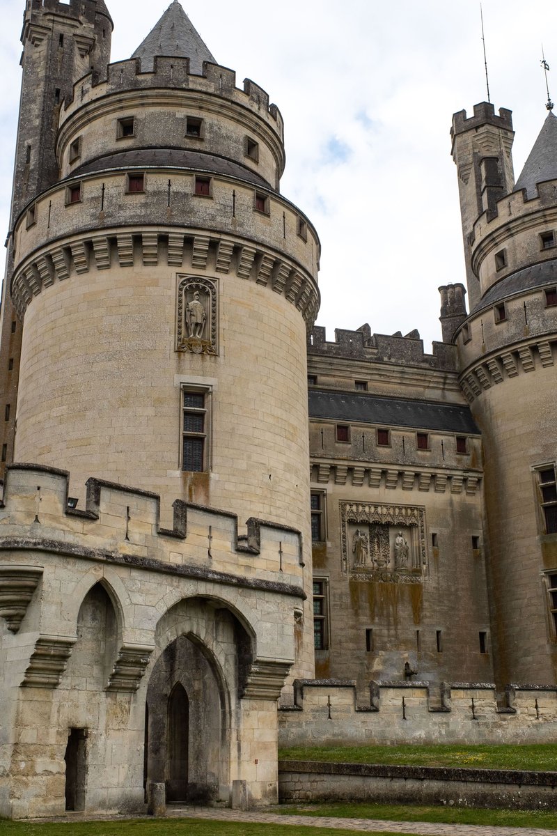 Das Château de Pierrefonds, das sich über dem Dorf erhebt – hoch aufragende Rundtürme, maschikulierte Wehrgänge und steile Kegeldächer, die im Licht gegen den Wald von Compiègne leuchten. Pierrefonds, Oise, Frankreich.