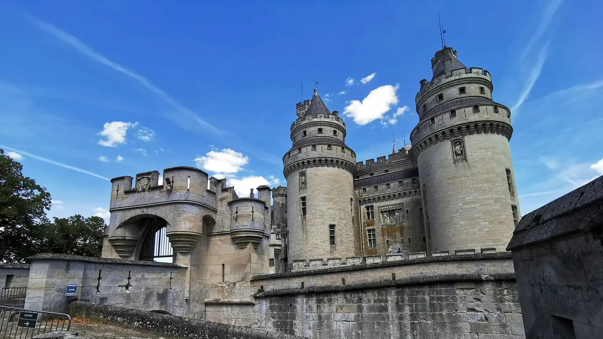 The gatehouse and two round towers of Château de Pierrefonds under a clear blue sky, Oise, France