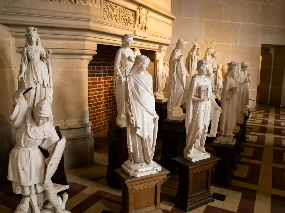 A row of white statues along a hall inside Château de Pierrefonds